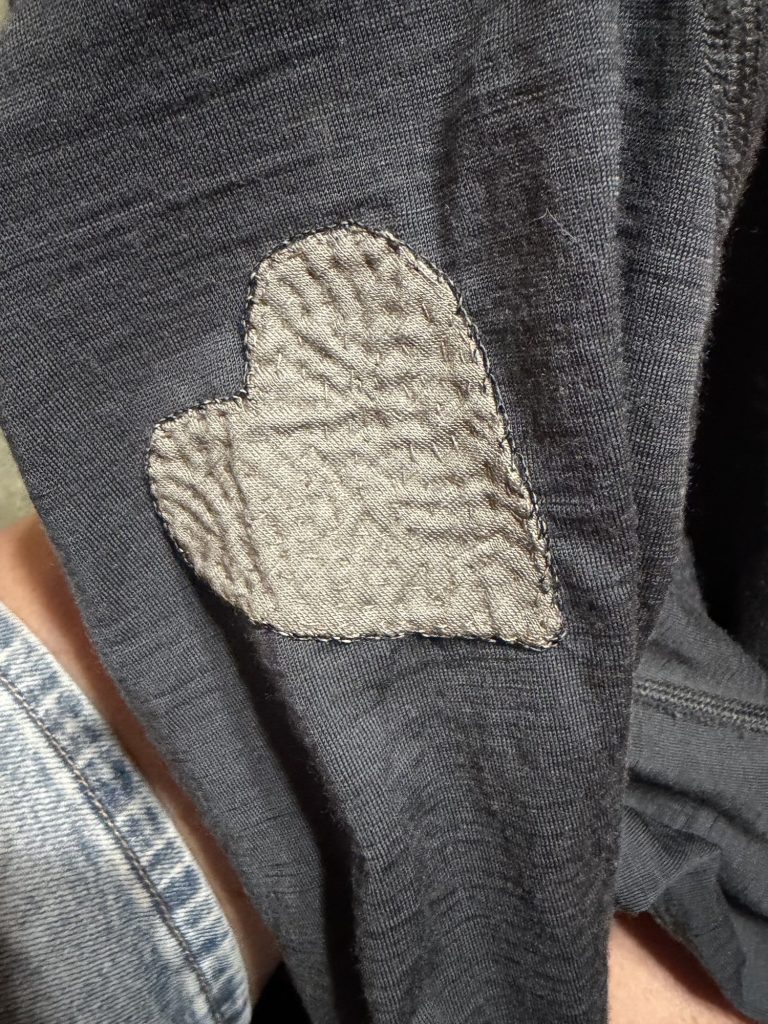 Photo of the outside of a shirt mended with a heart shaped appliqué patch. 