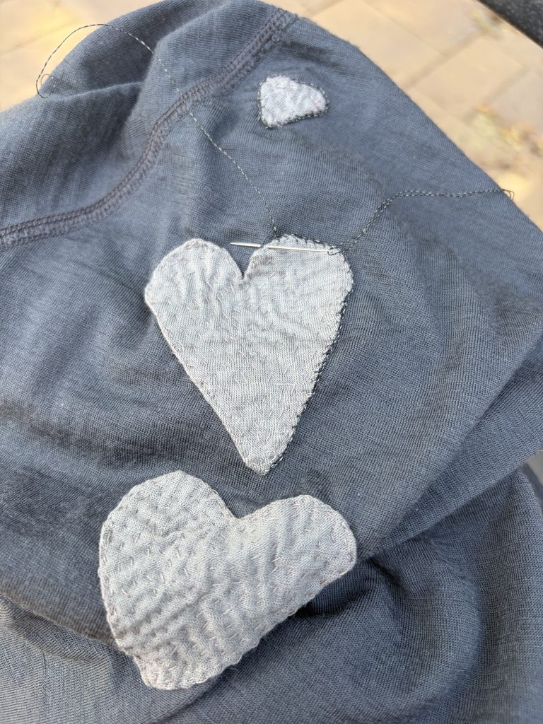 Heart shaped patches over multiple moth holes on a wool running shirt.