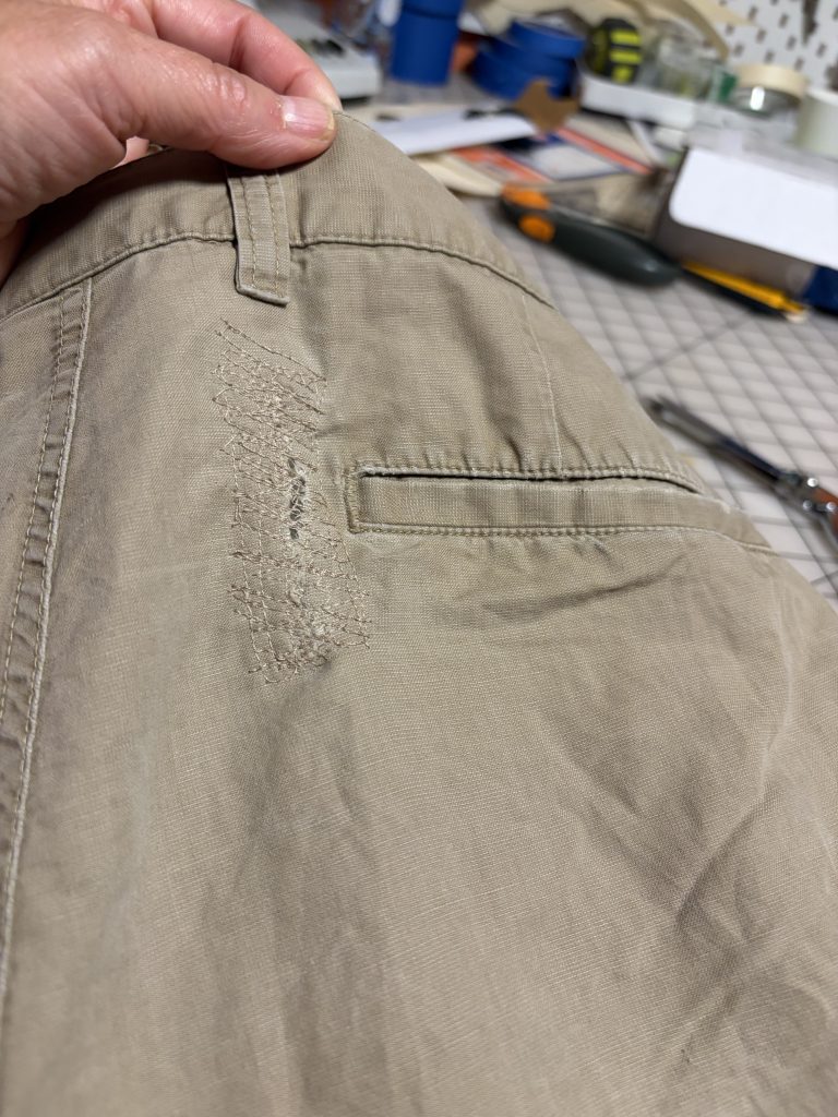 The hole mended with a patch that has been top stitched 