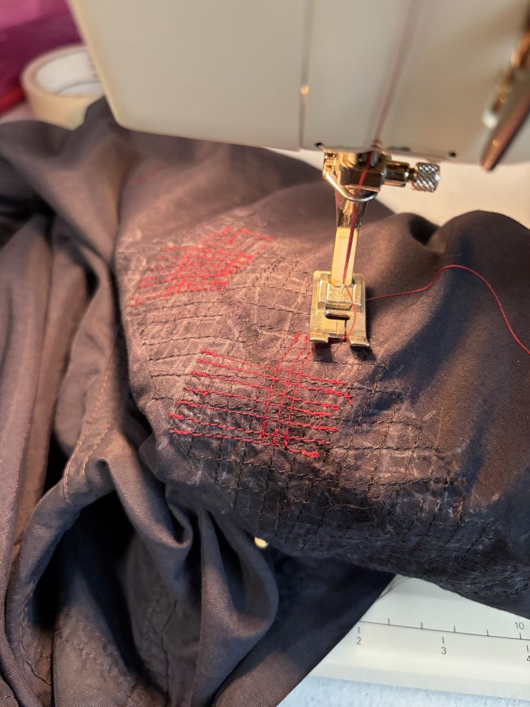 A patch being securely stitched in place in a decorative style over a large rip in running shorts.